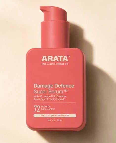 A cropped studio photo of the coral Arata serum bottle standing alone on a cream surface, the same bottle carried through every photograph in the set.