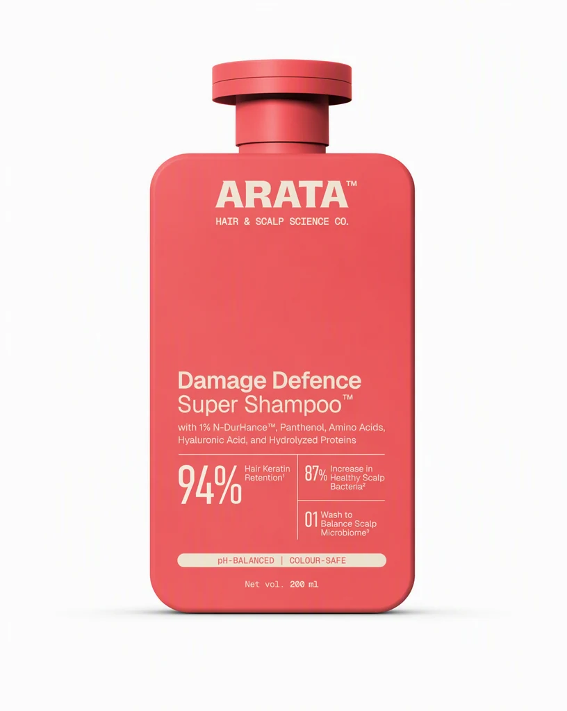 A coral red shampoo bottle standing straight on, centered on a plain white background with a soft contact shadow, styled like an unfinished catalog photo.